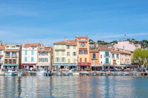 Buildings in front of harbor of Cassis France, their reflections are on the water in the bottom half of the photo.